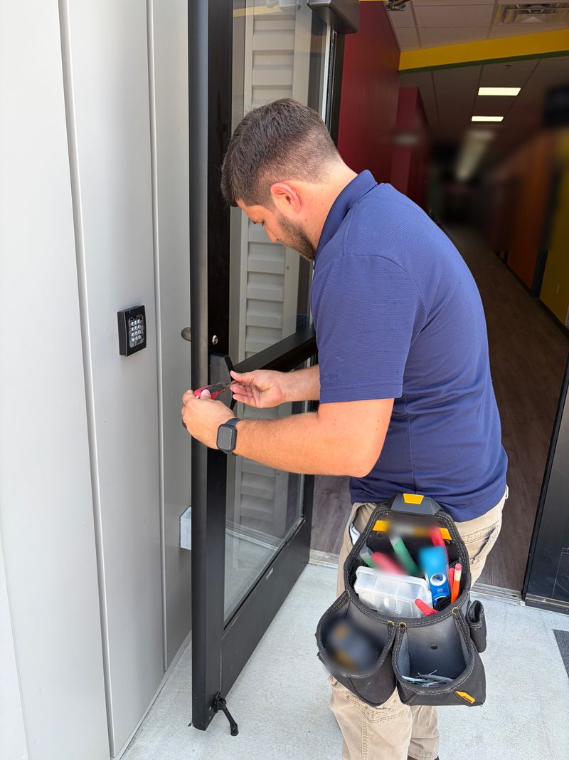 JCS technician working on a commercial glass door next to a keypad access reader